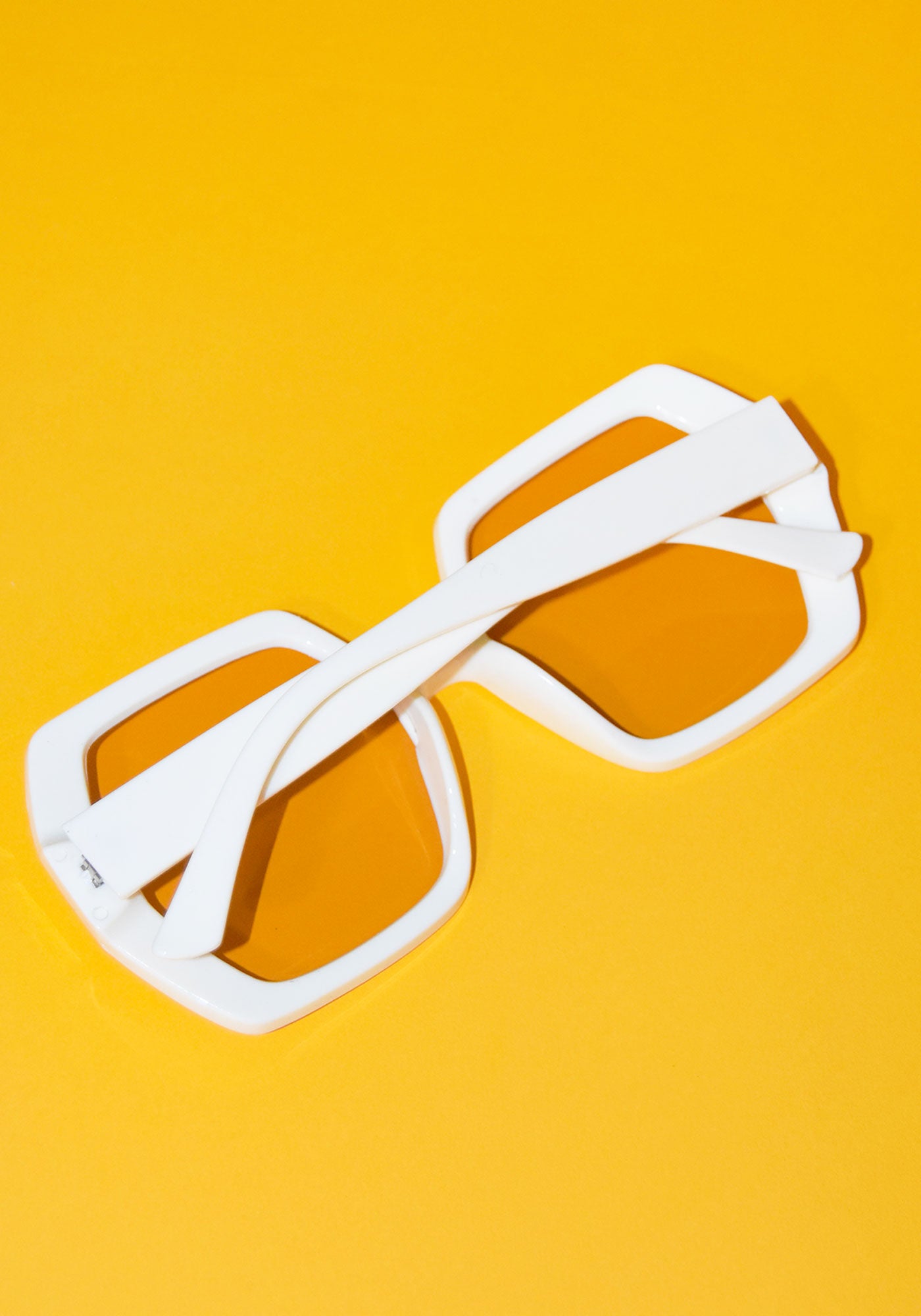 back orange and yellow background and squared ivory translucent ivory sunglasses